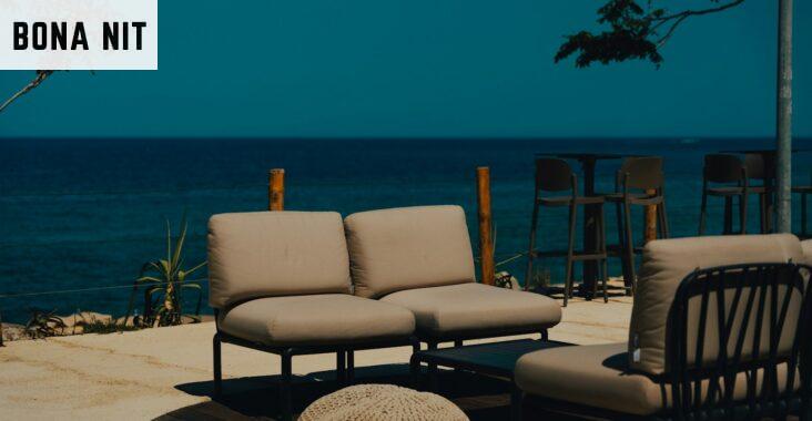 A couch and chair sitting on a patio next to the ocean