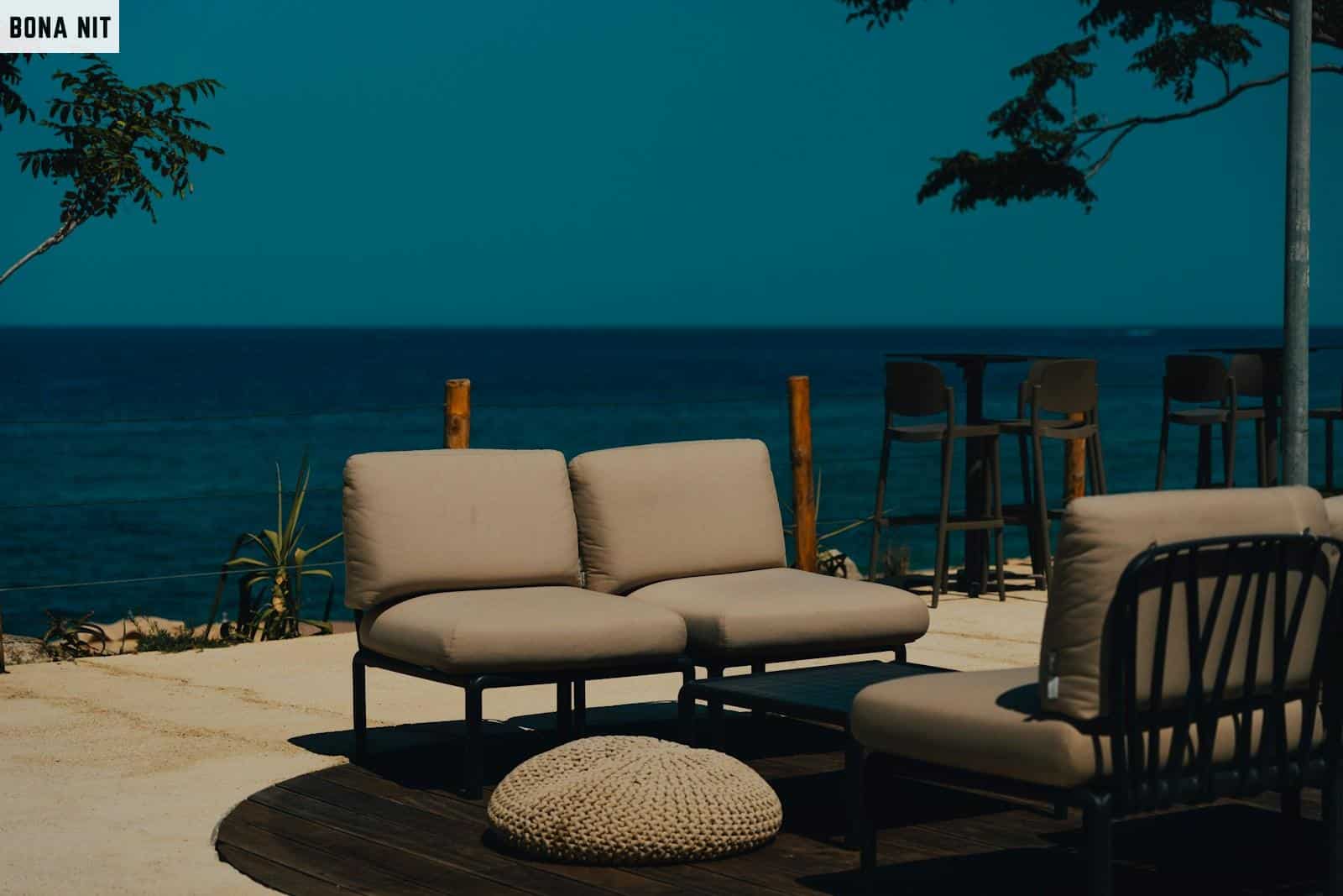 A couch and chair sitting on a patio next to the ocean
