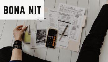 person holding paper near pen and calculator